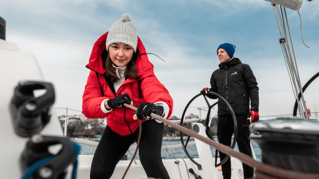 Man and woman pulling sailing ropes in winter clothing